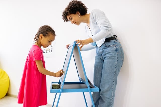 Child writing on board with teacher